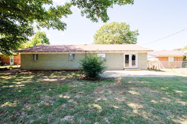 rear view of house with french doors, a patio area, and a lawn