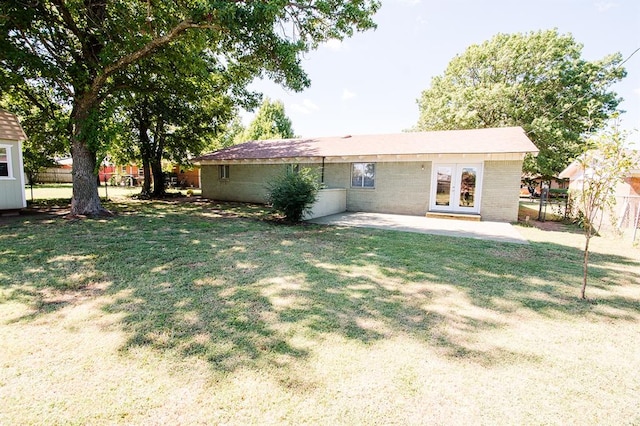 rear view of house featuring french doors, a patio area, and a lawn