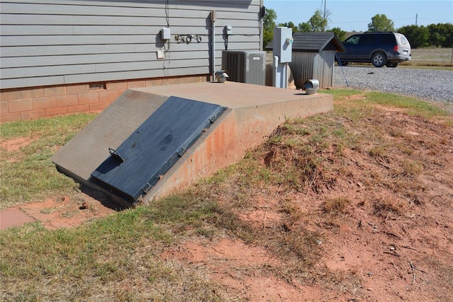 view of storm shelter with a storage unit and central AC unit