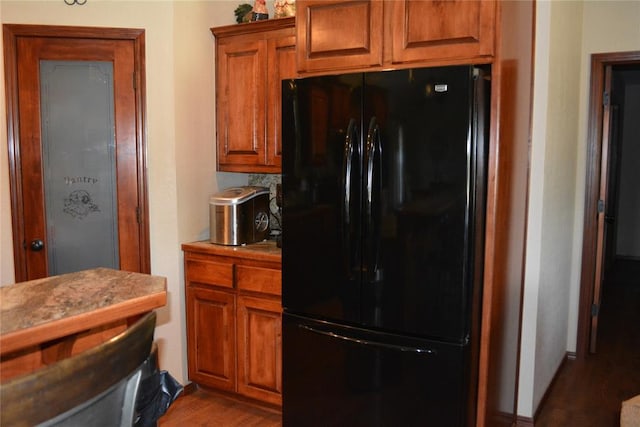 kitchen with black fridge and dark wood-type flooring