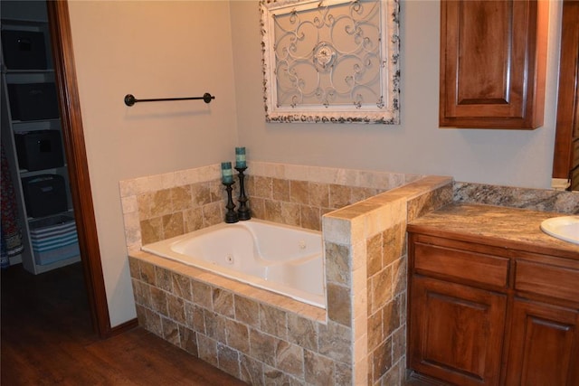 bathroom featuring hardwood / wood-style floors, vanity, and a relaxing tiled tub