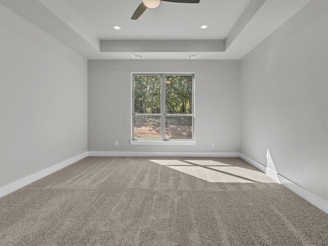 carpeted spare room with ceiling fan and a tray ceiling