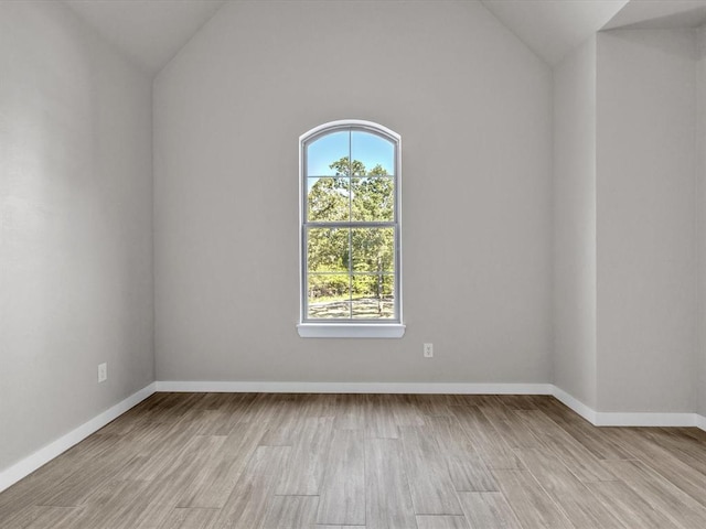 spare room featuring light hardwood / wood-style floors and lofted ceiling