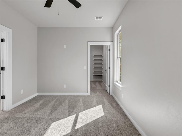 unfurnished bedroom with carpet flooring, ceiling fan, a walk in closet, and a closet