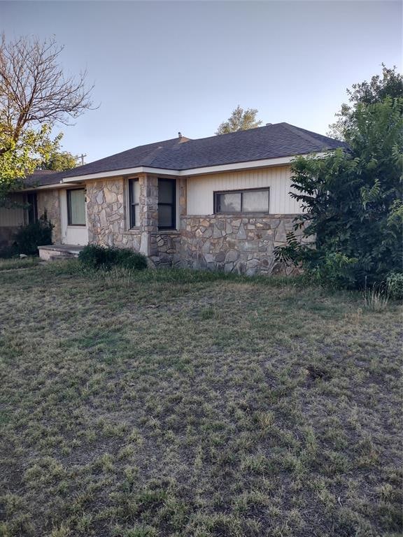 ranch-style house featuring stone siding and a front lawn