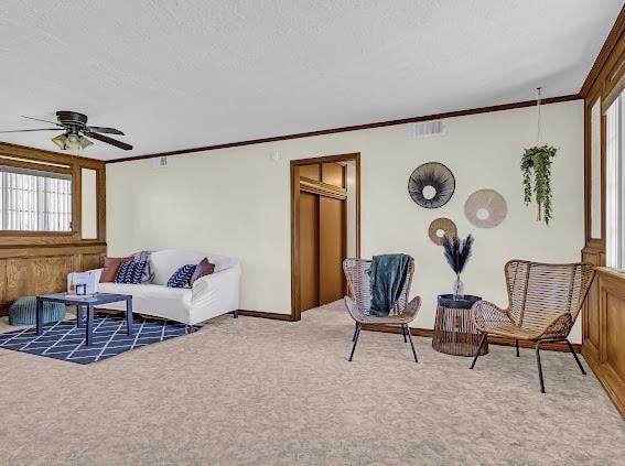 living room with ceiling fan, carpet, and ornamental molding