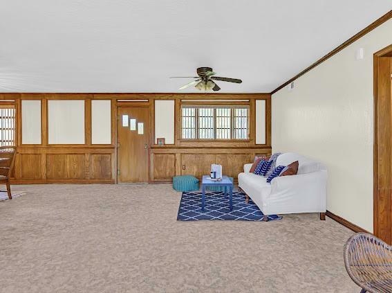 carpeted living room featuring ceiling fan and crown molding