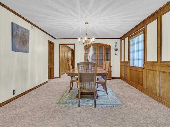 carpeted dining area featuring a notable chandelier and crown molding