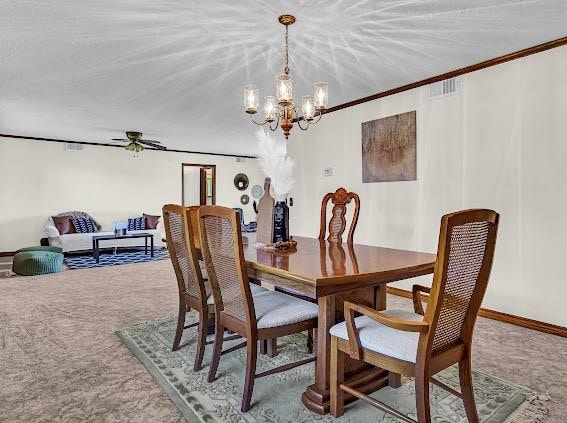 carpeted dining room featuring crown molding and ceiling fan with notable chandelier