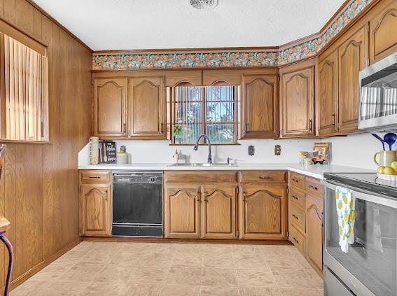 kitchen with wooden walls, sink, and appliances with stainless steel finishes