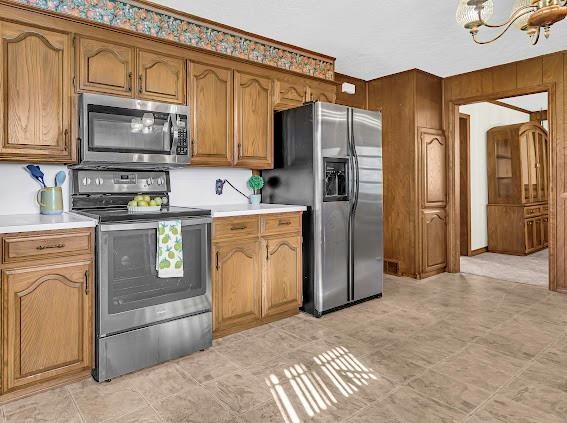 kitchen featuring a chandelier, appliances with stainless steel finishes, and wooden walls