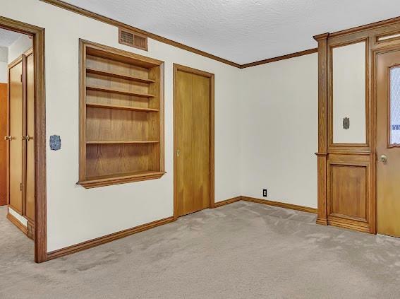 unfurnished bedroom featuring light carpet, crown molding, and a textured ceiling