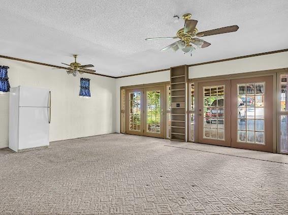 unfurnished living room featuring french doors, carpet floors, a textured ceiling, and ceiling fan