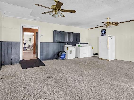 interior space featuring ceiling fan, wooden walls, white fridge, and washer and dryer