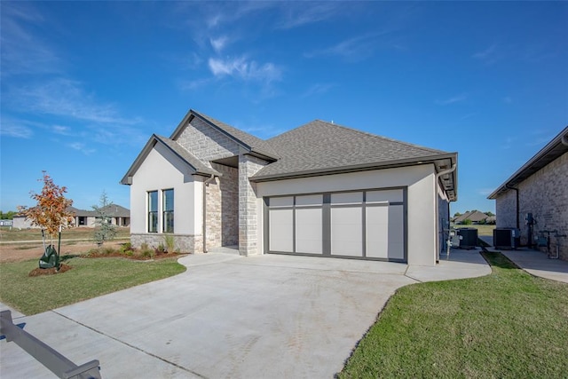 view of front of house with central AC unit, a front yard, and a garage