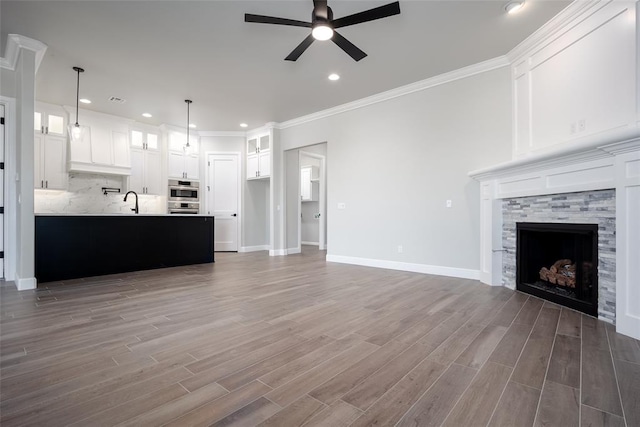 unfurnished living room with ceiling fan, a fireplace, dark hardwood / wood-style floors, and ornamental molding