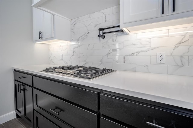 kitchen with decorative backsplash, white cabinetry, and stainless steel gas stovetop