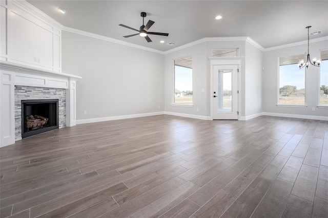 unfurnished living room with dark hardwood / wood-style floors, a stone fireplace, ceiling fan with notable chandelier, and crown molding