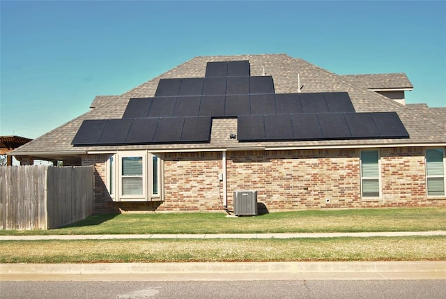 view of side of home with solar panels, a lawn, and central air condition unit