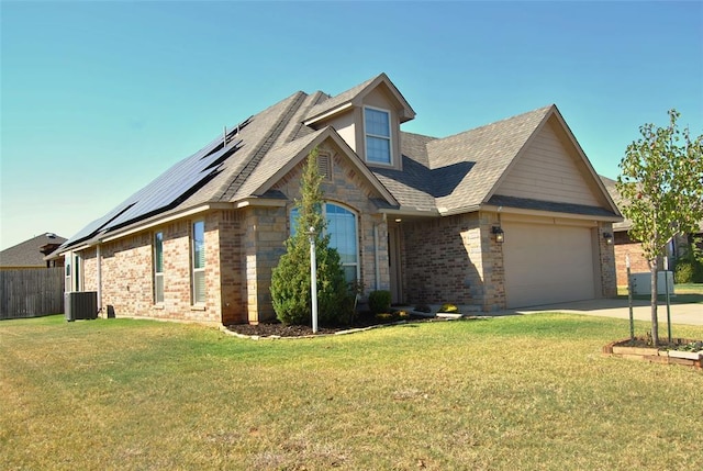 view of front of home featuring a front lawn, solar panels, a garage, and central AC