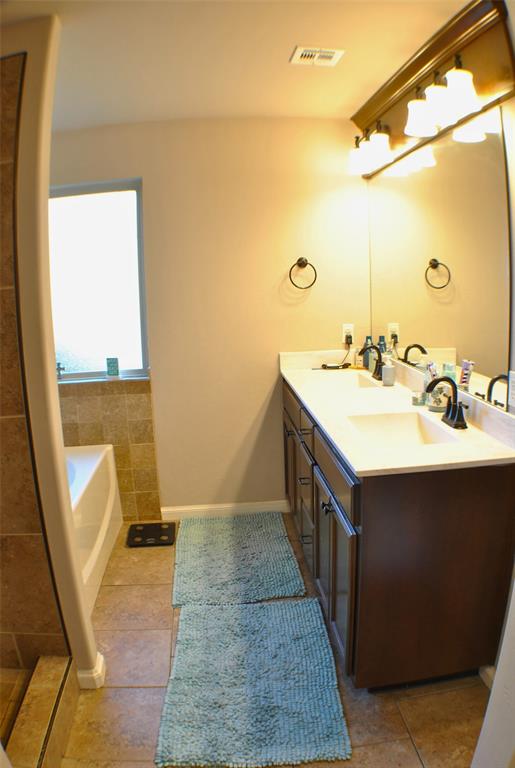 bathroom with tile patterned flooring, a bath, and vanity