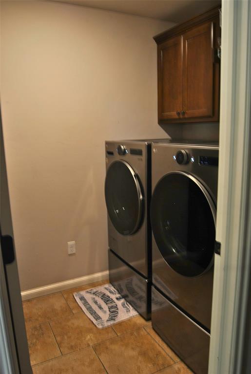 laundry room featuring cabinets, light tile patterned floors, and washing machine and dryer