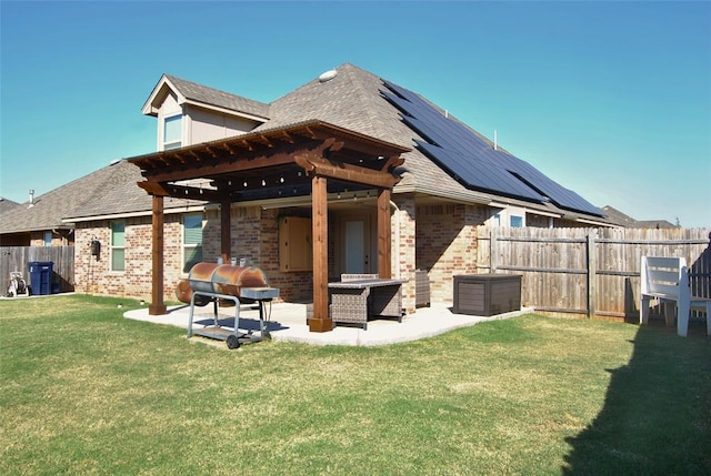 back of house with solar panels, a patio, a pergola, and a lawn