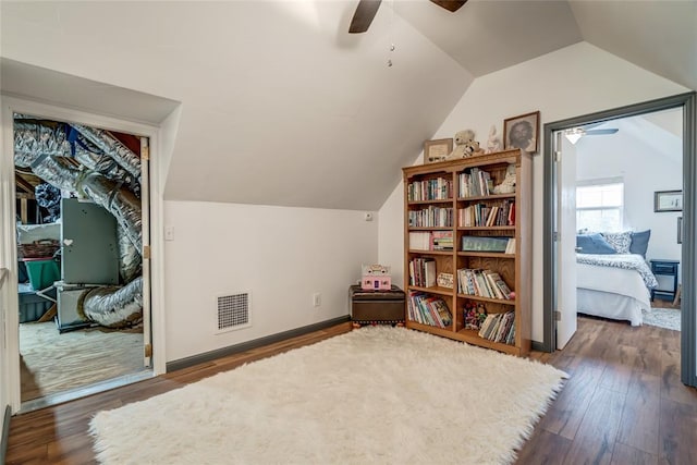 interior space with ceiling fan, vaulted ceiling, wood finished floors, and visible vents
