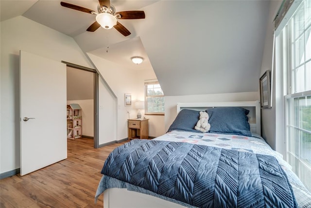 bedroom with ceiling fan, vaulted ceiling, and wood finished floors