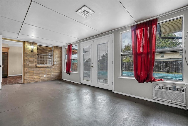 spare room featuring french doors, concrete floors, visible vents, and a healthy amount of sunlight