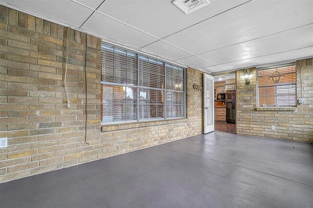 interior space featuring brick wall, concrete floors, and visible vents