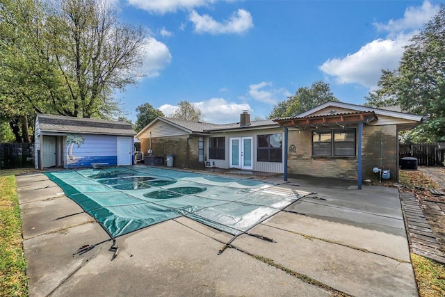 view of front of property with a fenced in pool, fence, french doors, a patio area, and brick siding