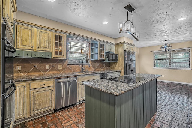 kitchen featuring a sink, a kitchen island, black appliances, tasteful backsplash, and glass insert cabinets