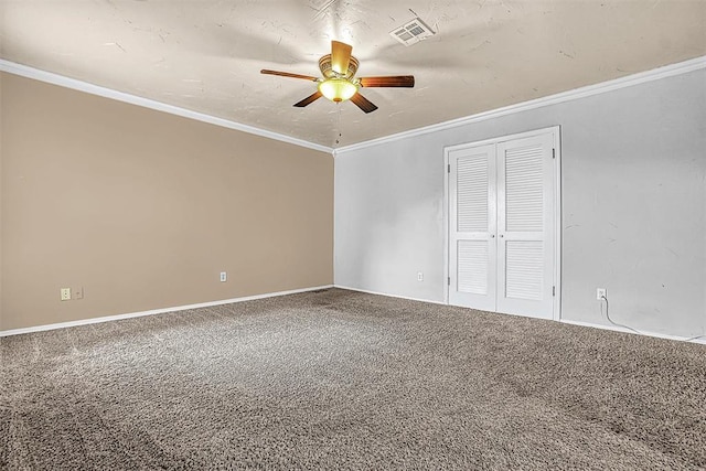 carpeted empty room with a ceiling fan, visible vents, and crown molding