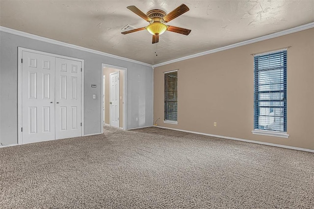 carpeted spare room featuring baseboards, ornamental molding, and a ceiling fan