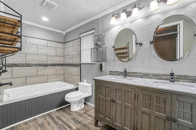 bathroom featuring a tub to relax in, crown molding, visible vents, toilet, and a sink