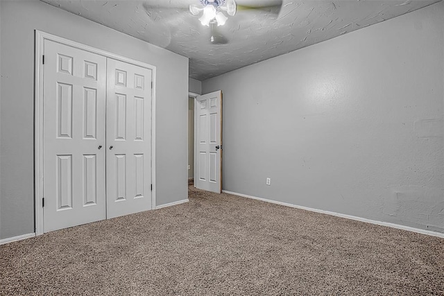 unfurnished bedroom featuring a textured ceiling, ceiling fan, carpet floors, baseboards, and a closet