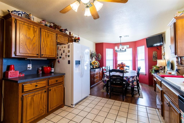 kitchen with sink, white refrigerator with ice dispenser, pendant lighting, light hardwood / wood-style floors, and ceiling fan with notable chandelier