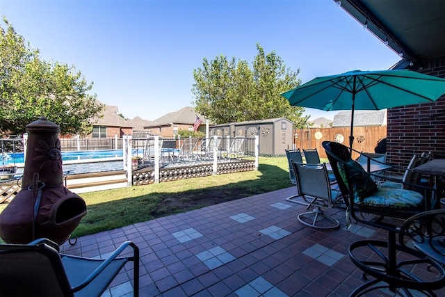 view of patio featuring a fenced in pool and a storage unit