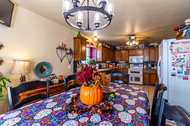 tiled dining space with ceiling fan with notable chandelier, sink, and a textured ceiling