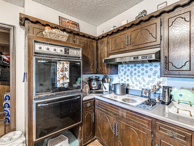 kitchen featuring decorative backsplash, dark brown cabinets, a textured ceiling, double oven, and stainless steel stovetop