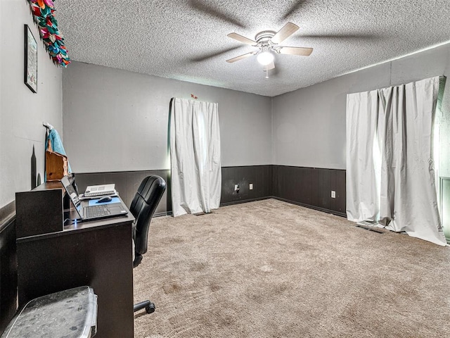 office space featuring ceiling fan, wood walls, a textured ceiling, and light carpet