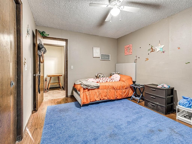 bedroom with ceiling fan, wood-type flooring, and a textured ceiling