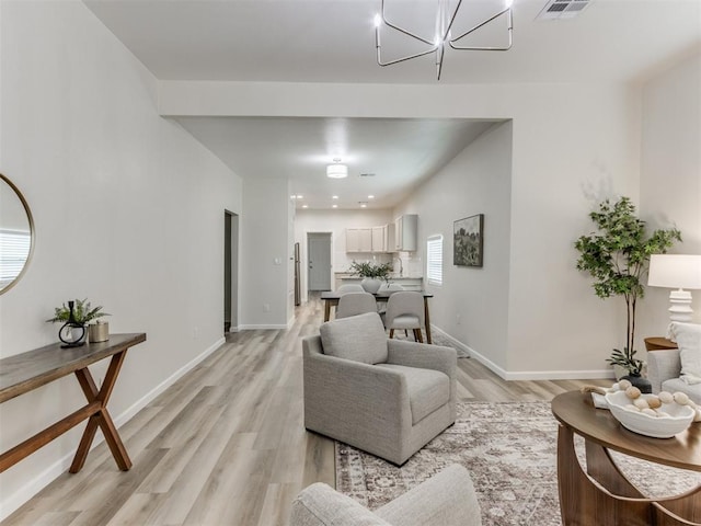 living room featuring light wood-type flooring and an inviting chandelier