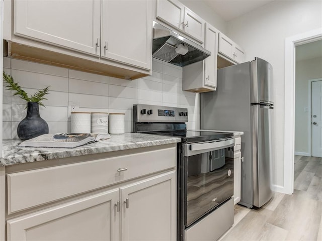 kitchen featuring light stone countertops, decorative backsplash, stainless steel appliances, light hardwood / wood-style flooring, and white cabinetry