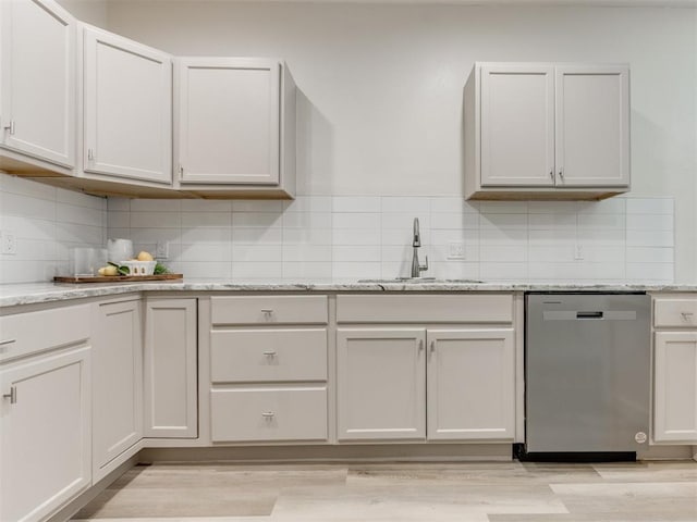 kitchen featuring dishwasher, white cabinets, sink, light hardwood / wood-style floors, and light stone counters