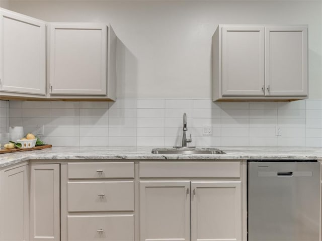 kitchen with stainless steel dishwasher, decorative backsplash, white cabinetry, and sink