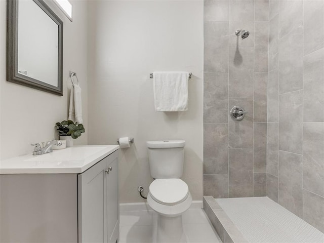 bathroom featuring tile patterned floors, toilet, vanity, and tiled shower