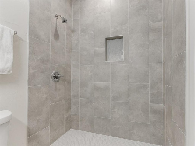 bathroom featuring a tile shower and toilet