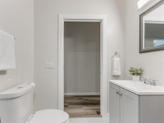 bathroom with toilet, vanity, and hardwood / wood-style flooring